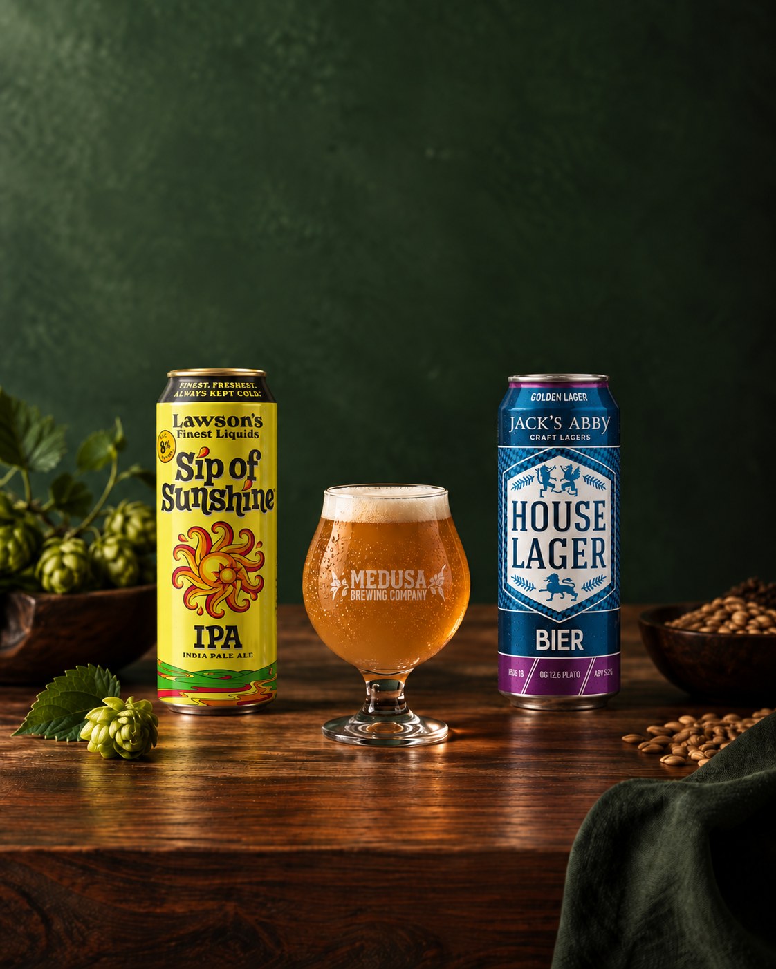 Lawson’s Sip of Sunshine and Jack’s Abby House Lager cans beside a glass of beer on a walnut table